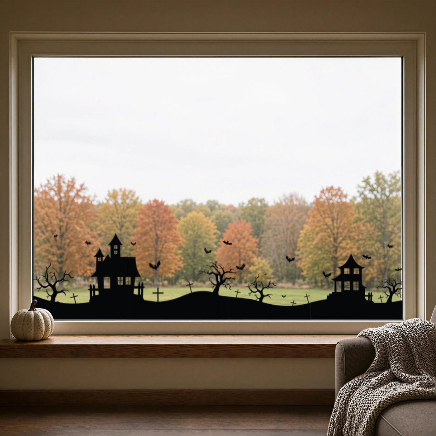 Haunted Village Halloween window clings — a black silhouette skyline of haunted houses, bare trees, graveyard crosses and bats along the bottom of a picture window