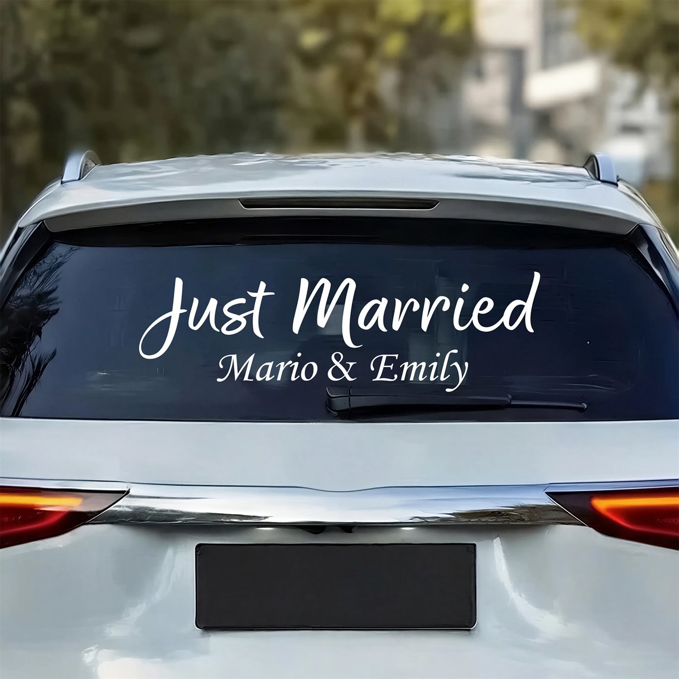 Personalized Just Married car decal in matte white cut vinyl on a car rear window with the couple's names underneath